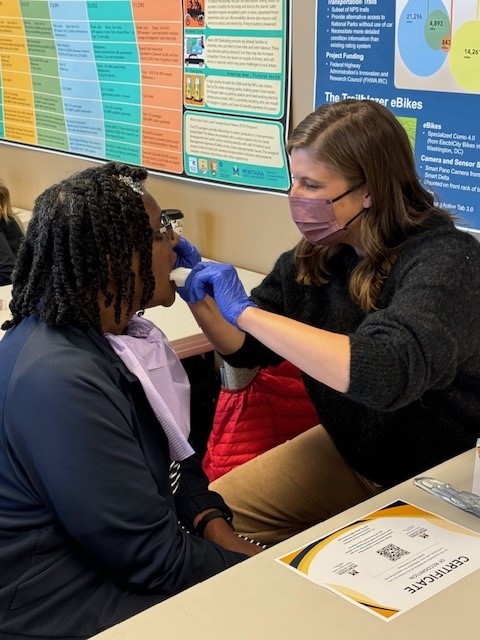 student applies fluoride varnish